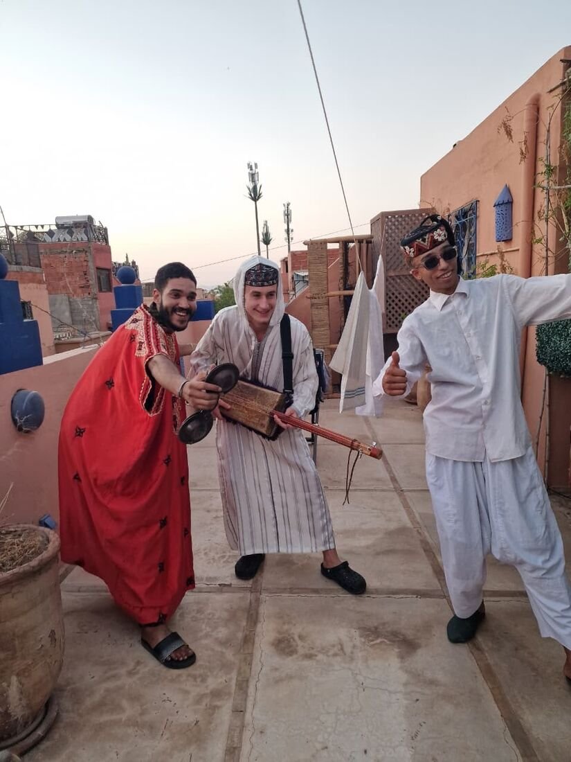 Trois musiciens Gnawa souriants sur un rooftop